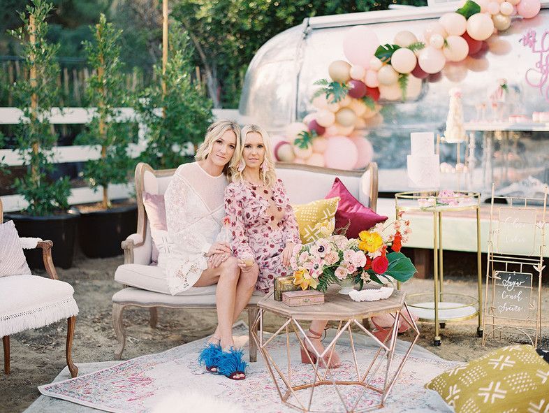 Two women are sitting on a couch next to a table.