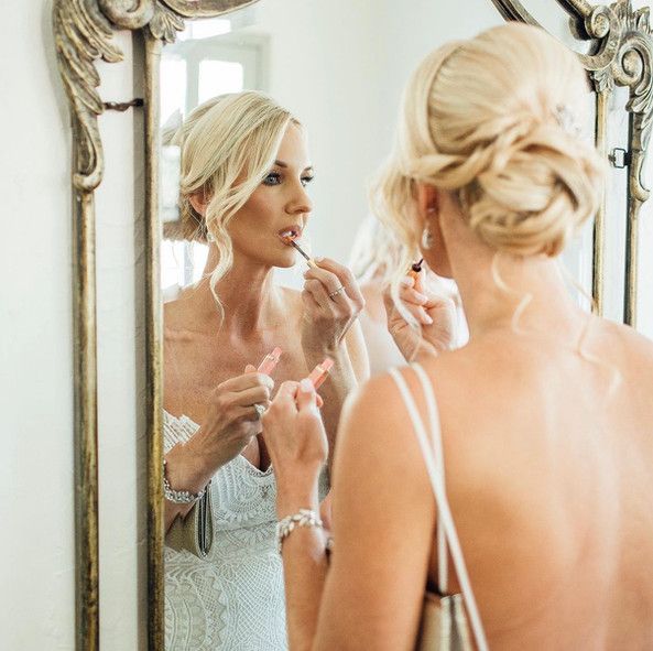 A woman is applying lipstick in front of a mirror.