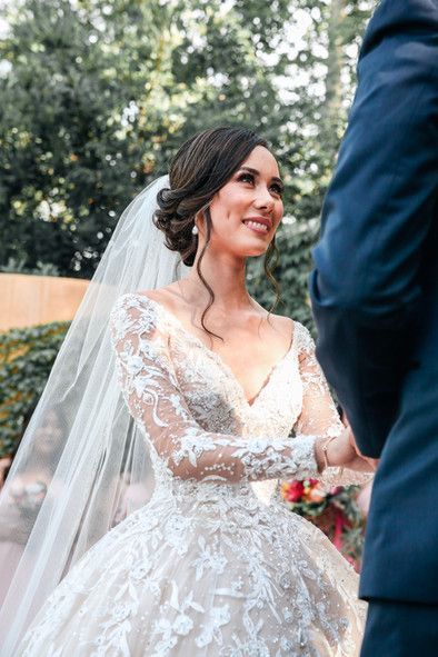 A bride in a wedding dress and veil is standing next to a groom in a suit.
