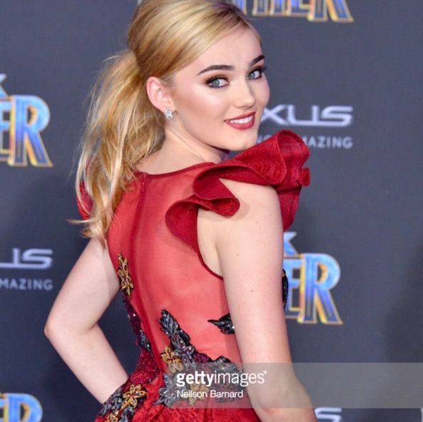 A woman in a red dress is standing on a red carpet.
