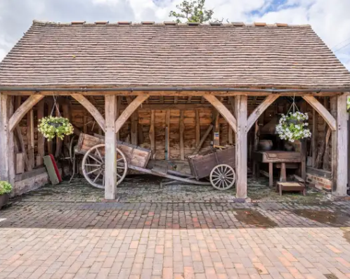A wooden barn with a horse drawn carriage inside of it.