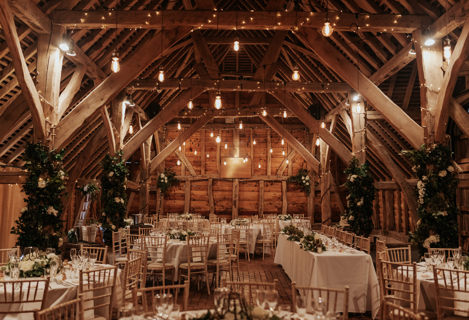 A large barn filled with tables and chairs for a wedding reception.