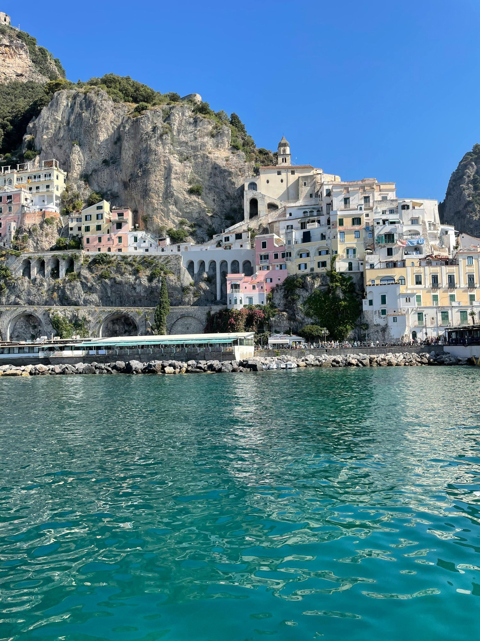 Town nestled on cliffs, colorful with arched walkways by turquoise water under a clear blue sky on the Amalfi Coast  Italy.
