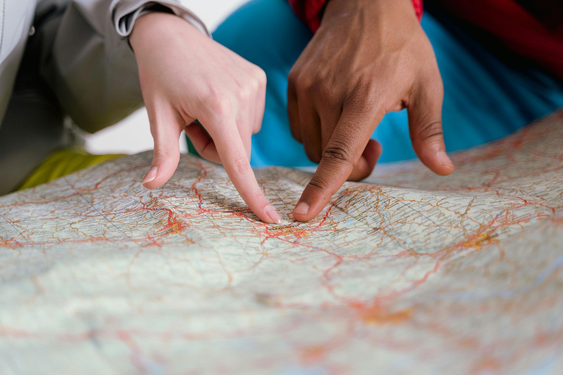 Two hands pointing at a detailed map, possibly planning a trip.