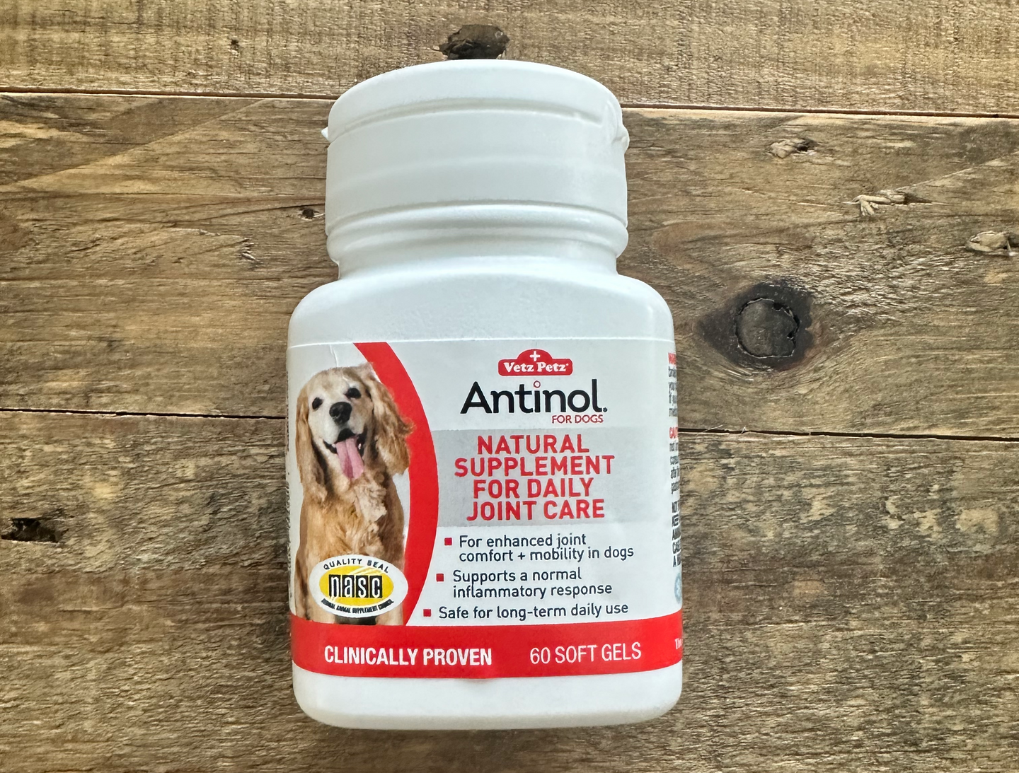 A bottle of antinol natural supplement for daily joint care is on a wooden table.