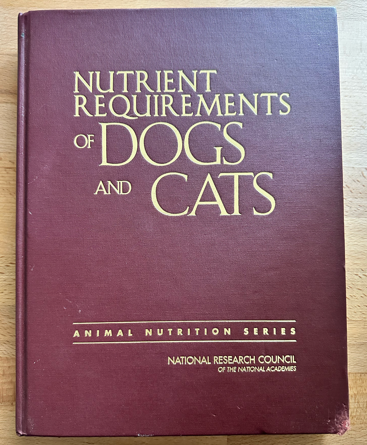 a book titled nutrient requirements of dogs and cats is sitting on a wooden table .
