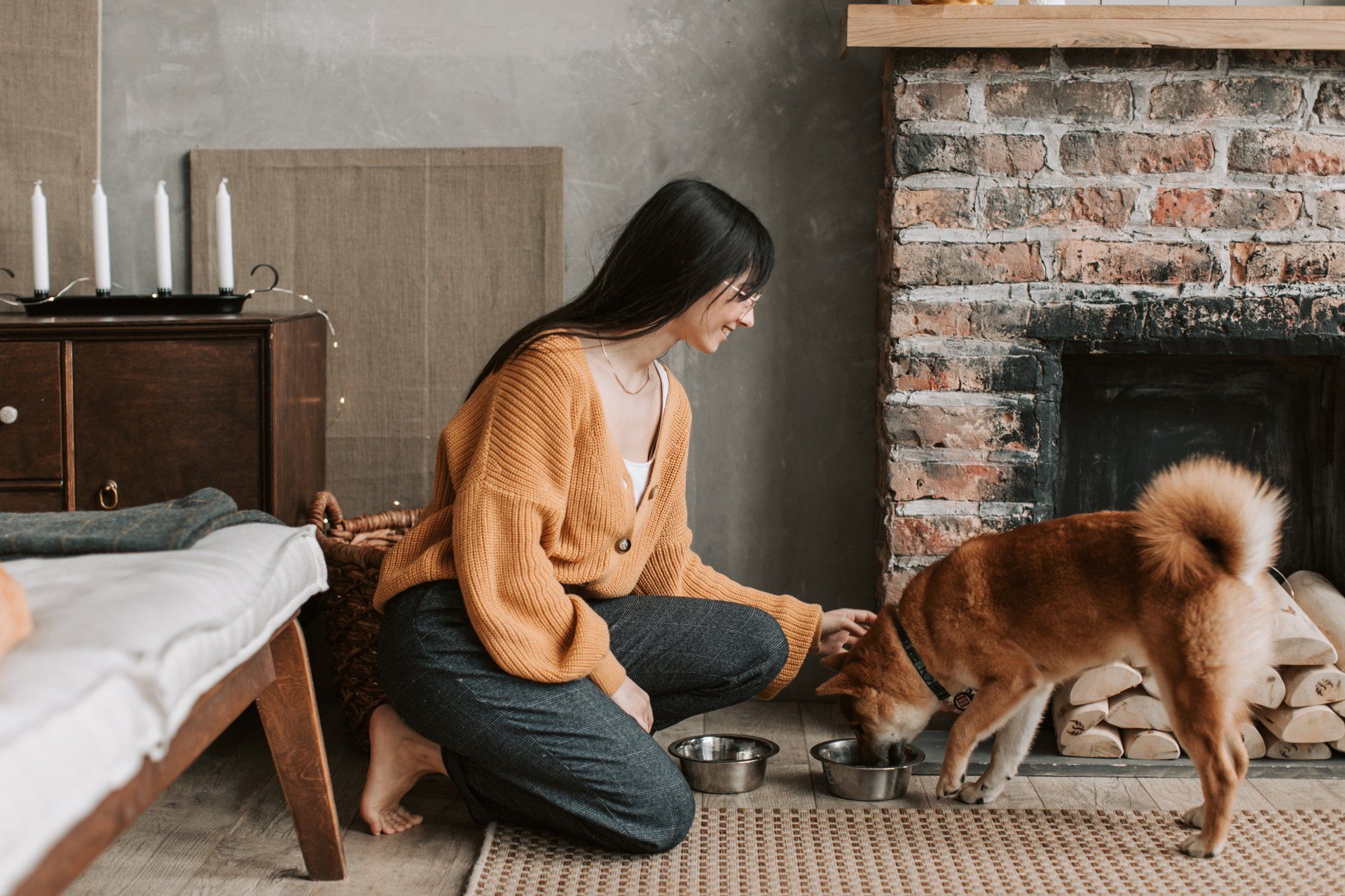 a woman is kneeling down to feed her dog in a living room .