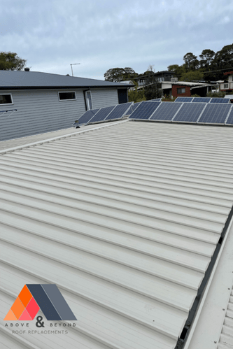 A Roof With Solar Panels On It And A House In The Background – Melbourne, VIC - Above & Beyond Roof Replacements