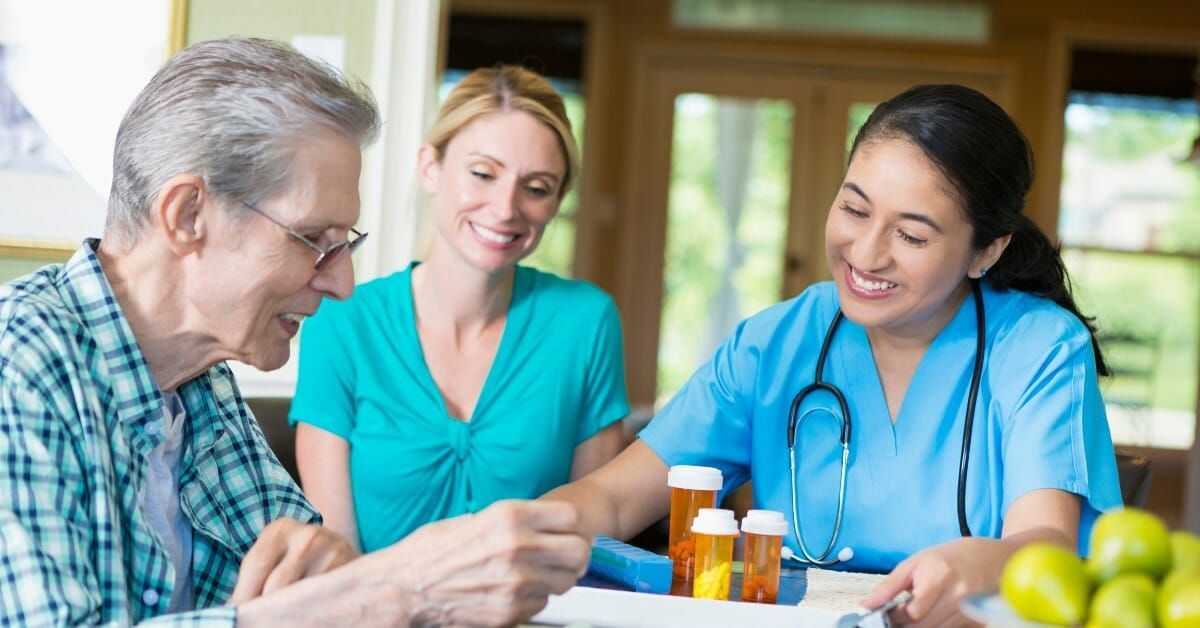 An elderly man is sitting at a table with a nurse and a doctor.