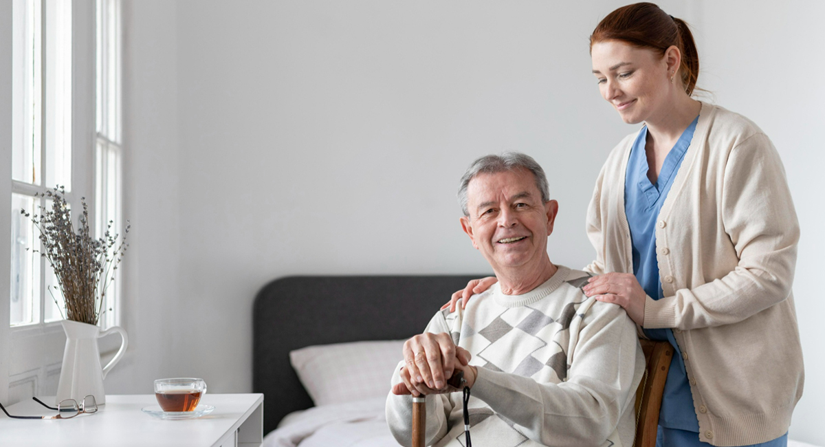 A nurse is standing next to an elderly man in a wheelchair.