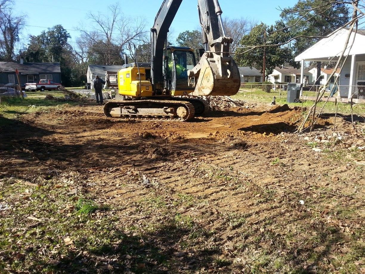 G&P construction using a yellow excavator is digging a hole in a dirt field.
