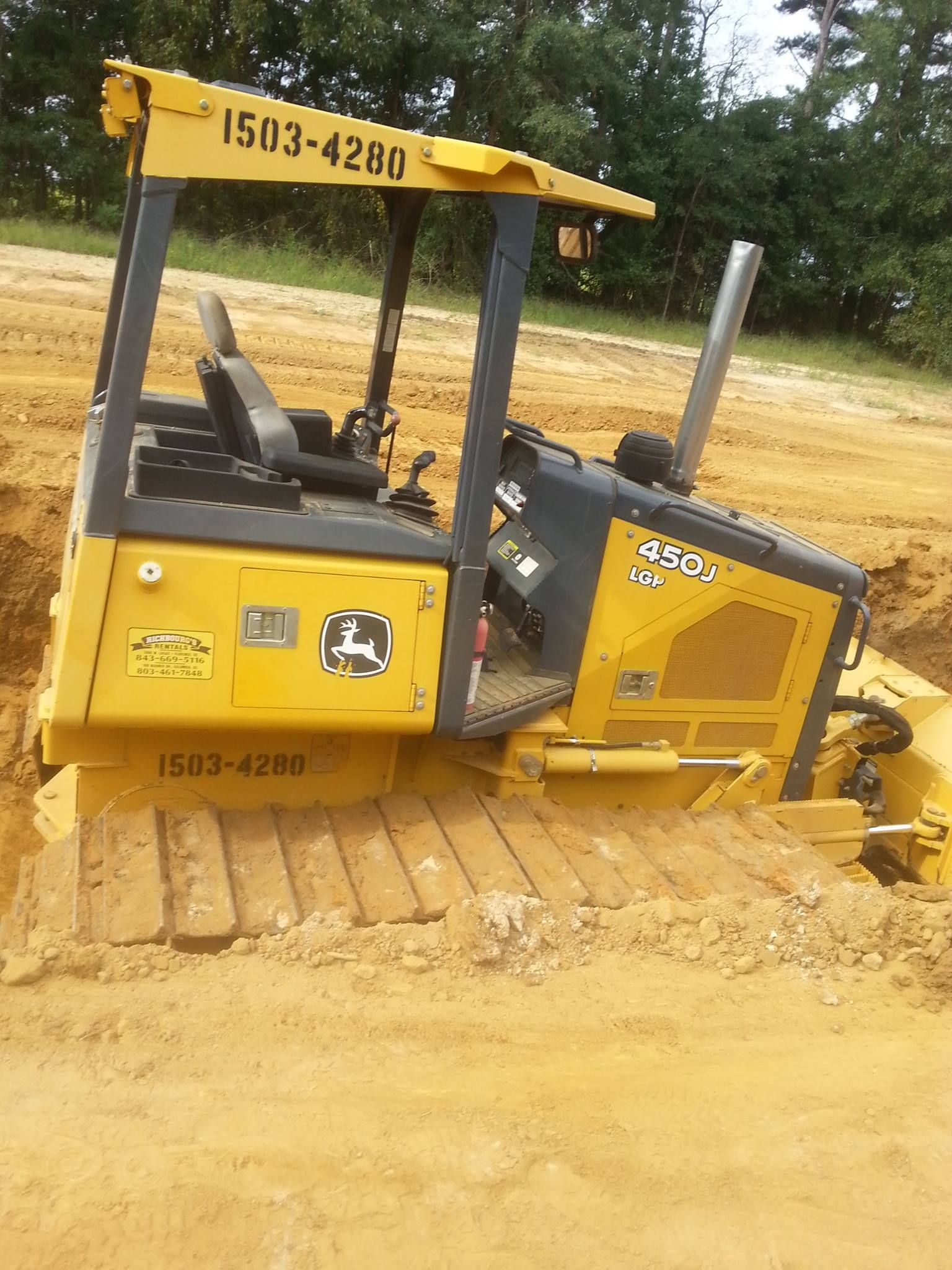 A yellow bulldozer is laying on its side in a dirt field.