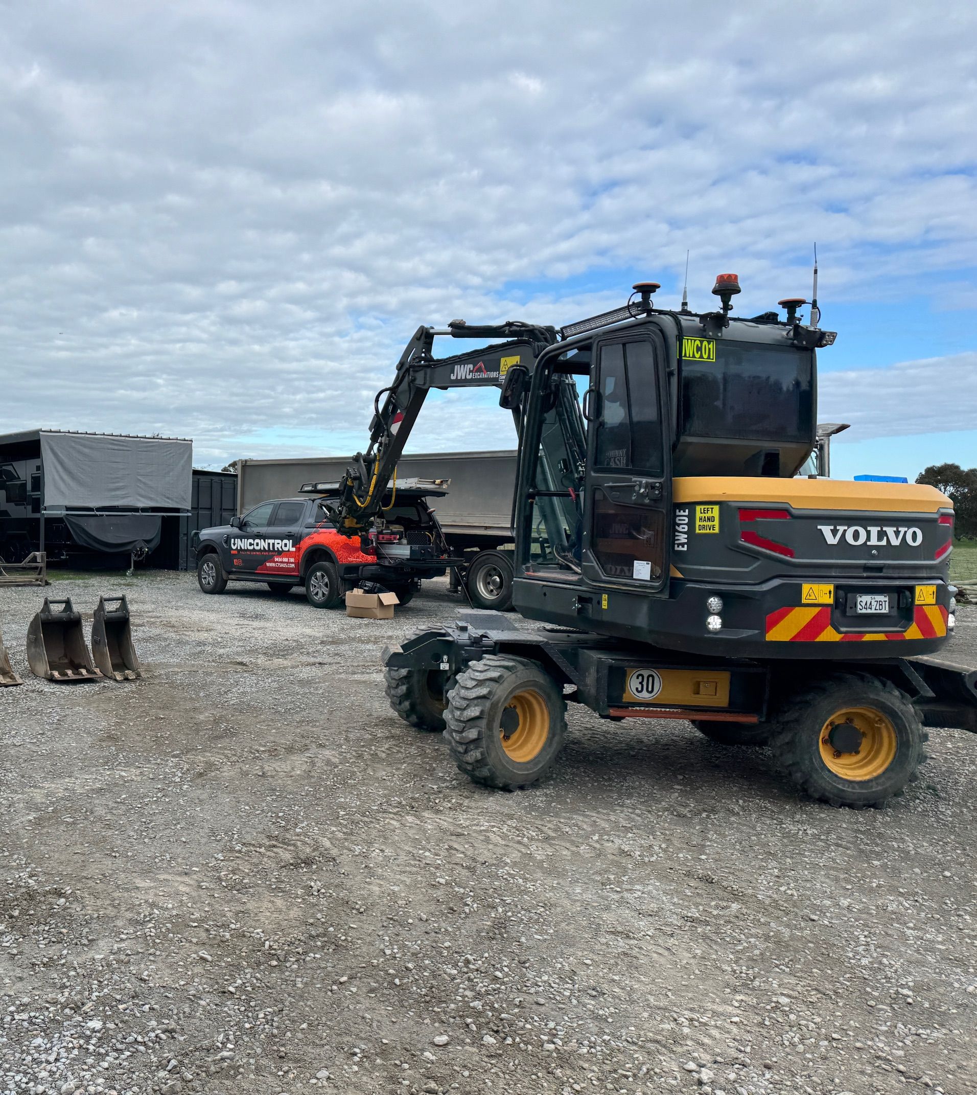 Yellow backhoe loading brown gravel onto a pile outdoors.