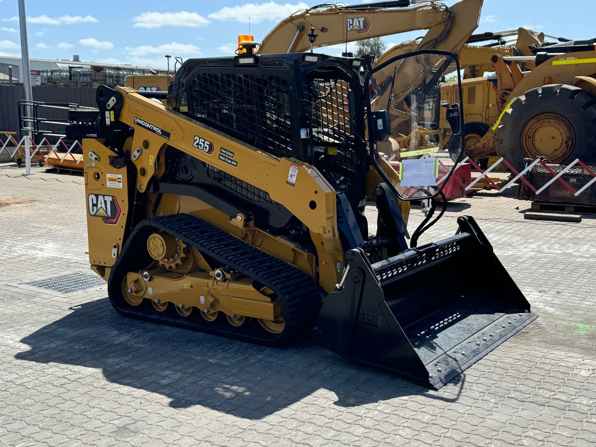 Yellow excavator working on dark soil; houses in background.