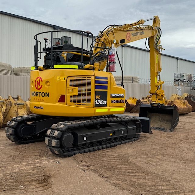 Aerial view of construction site with earth-moving equipment and debris on dirt ground.