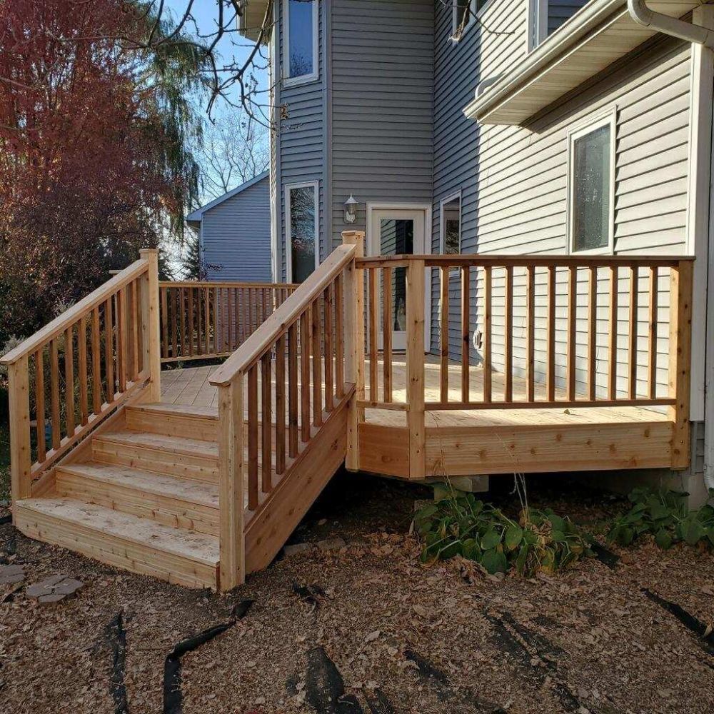 Wooden deck and stairs attached to a two-story gray house.