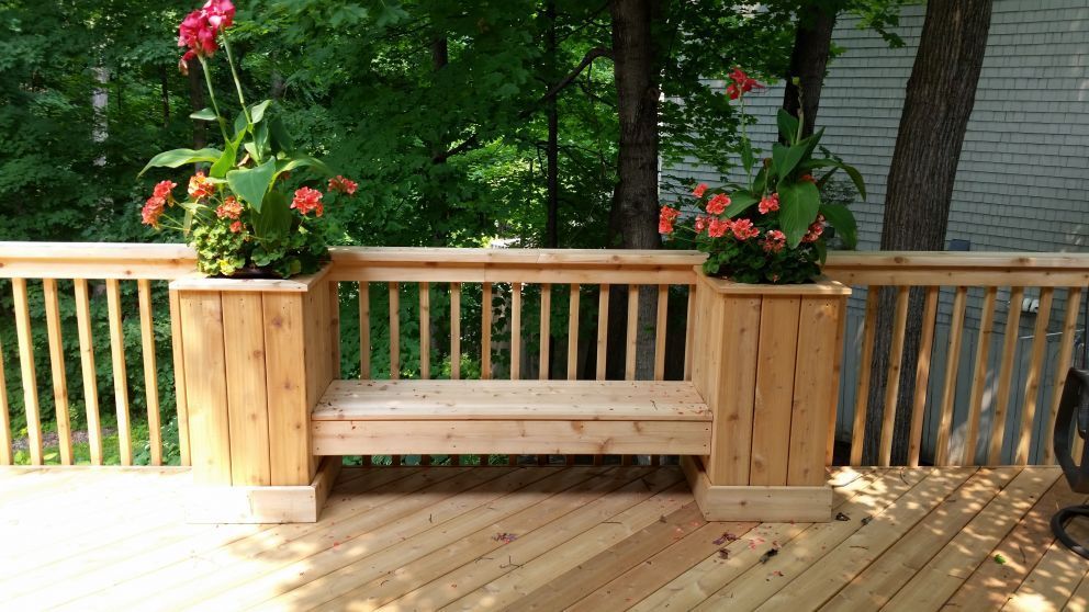 Wooden deck with a built-in bench and two planter boxes with orange flowers.