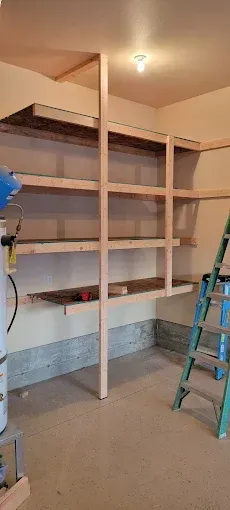 Wooden shelves being built in a garage. Ladder is nearby.