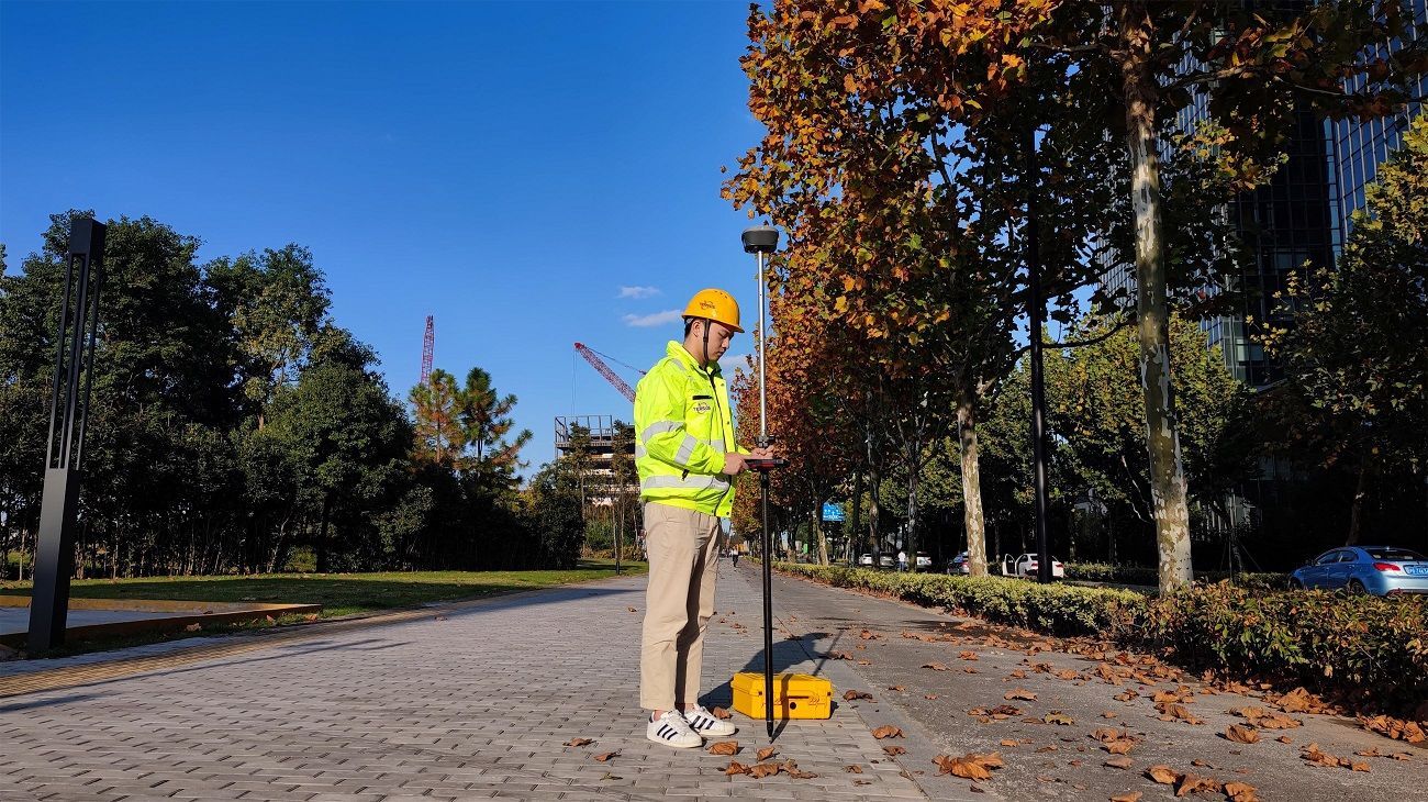 Um homem com capacete está parado na calçada de um parque.