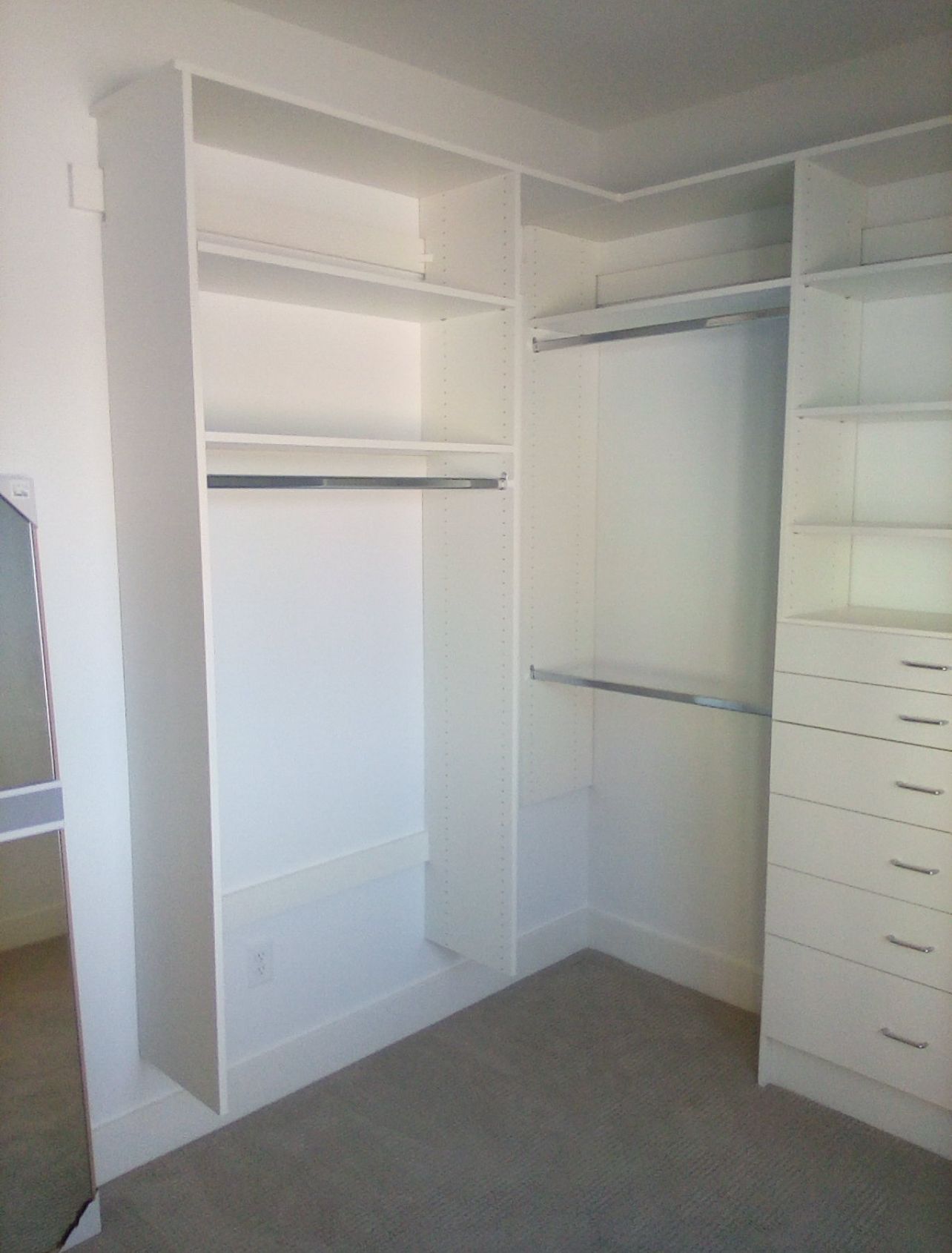 A walk in closet with lots of shelves and drawers