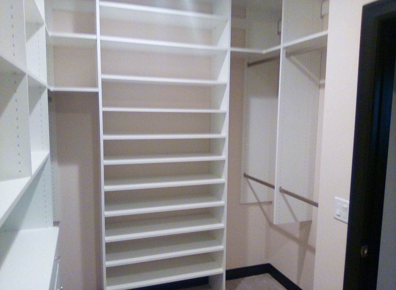 A walk in closet with lots of shelves and hangers