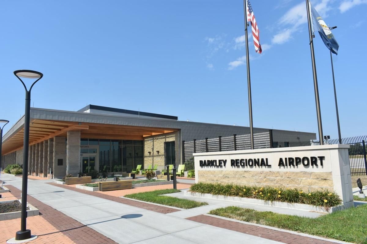 Exterior view of Barkley Regional Airport with flags and sign on a sunny day.