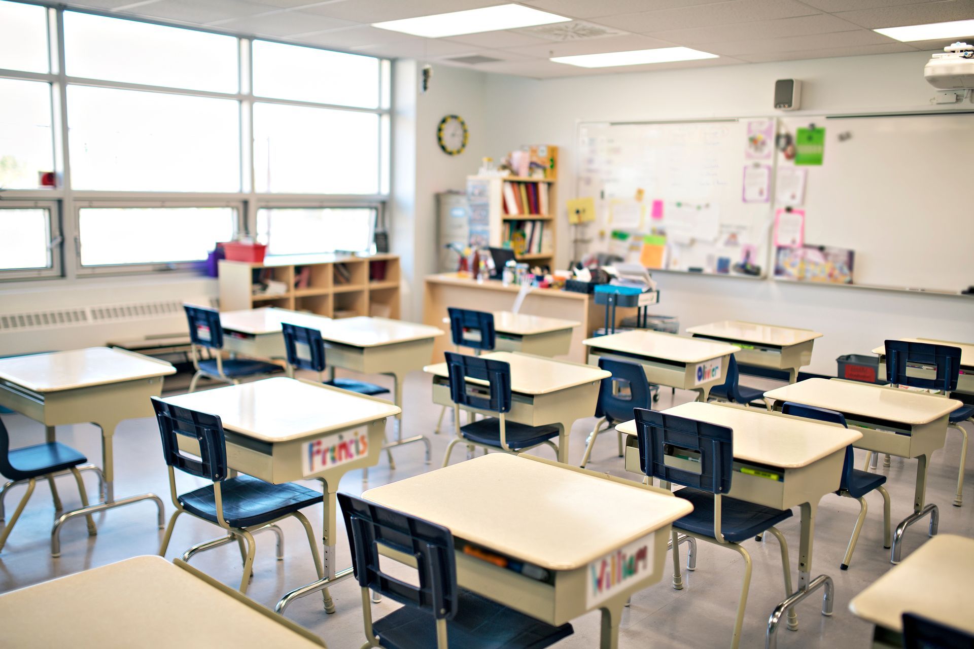 Empty classroom with desks, a whiteboard, and a window.