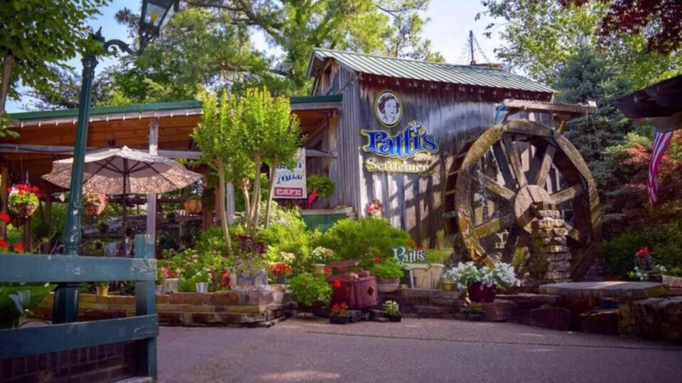 A quaint shop with a water wheel and flowers.