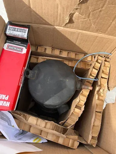 A cardboard box filled with a gray object and a red box.