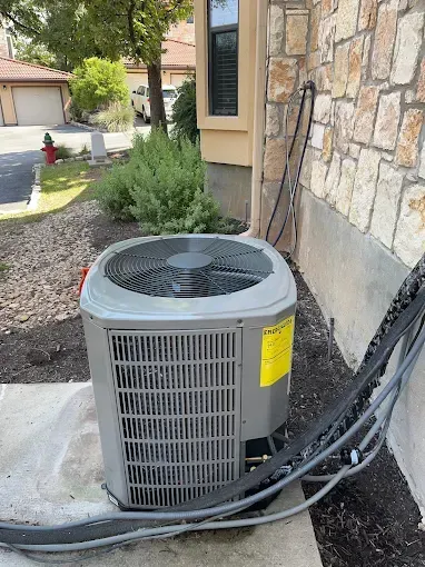 An air conditioner is sitting on the side of a house.