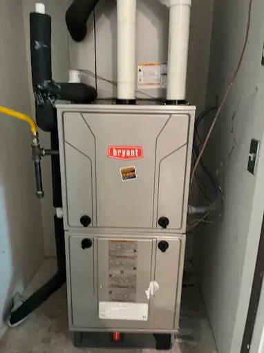 A bryant air conditioner is sitting in a room next to a wall.