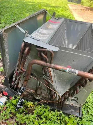 A broken air conditioner is sitting in the grass.