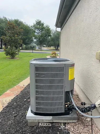 An air conditioner is sitting on the side of a house.