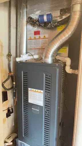 A gas furnace is sitting in a room next to a door.