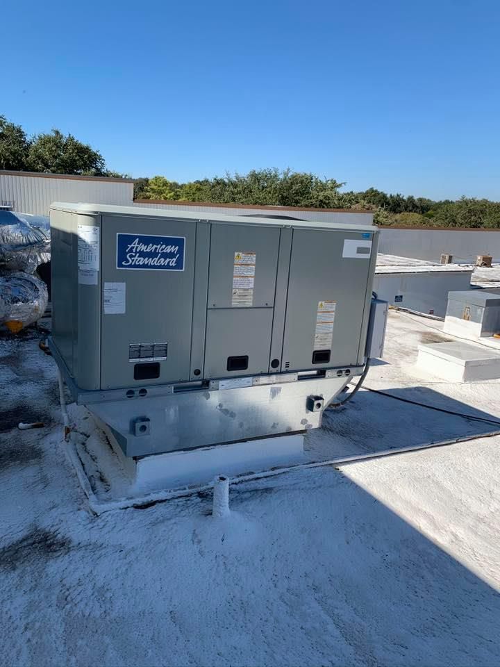 A large air conditioner is sitting on top of a white roof.