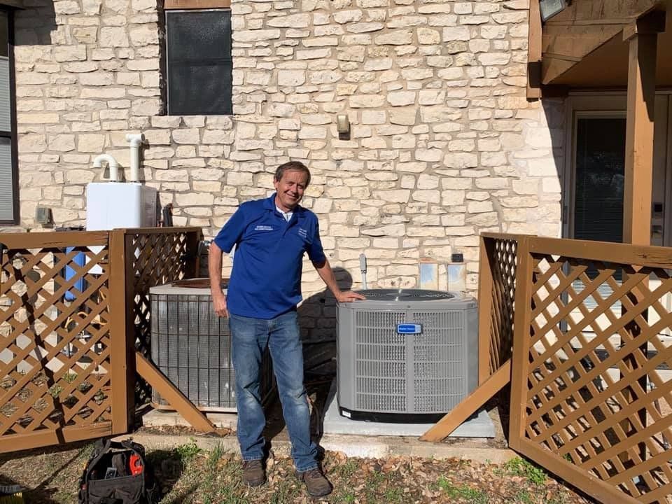 A man is standing next to an air conditioner in front of a brick building.