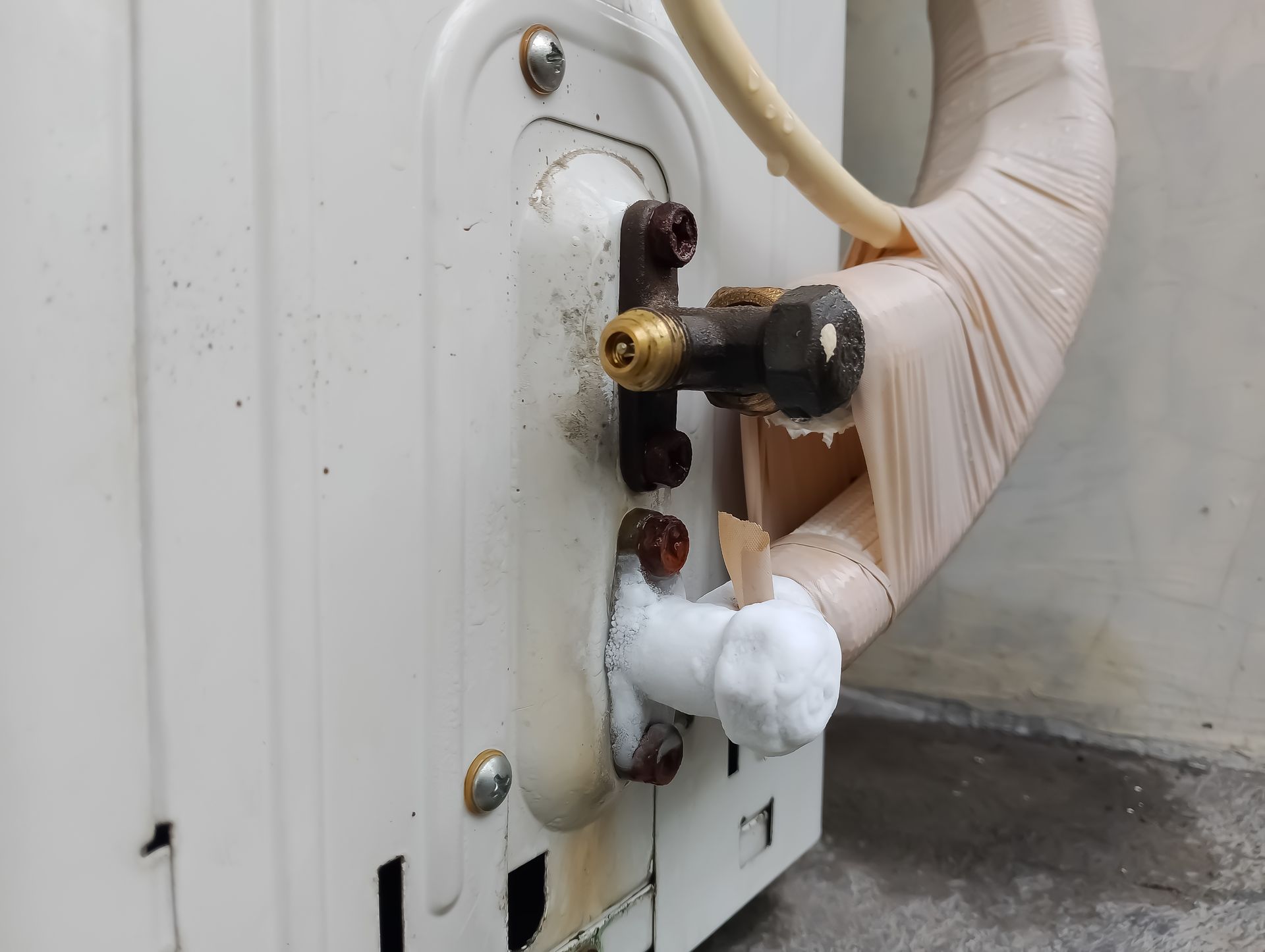 Outdoor AC unit with frost on copper tubing and rusted screws.