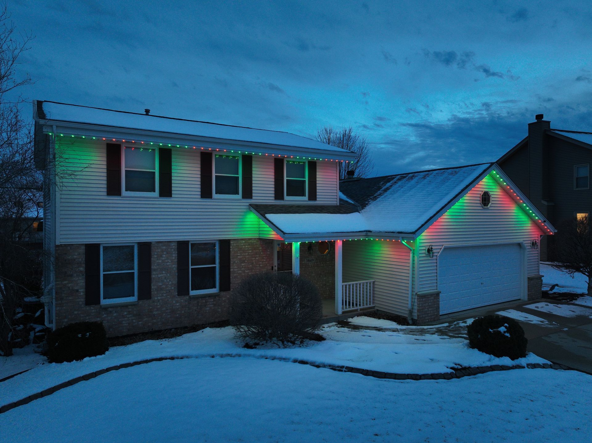 A house with Christmas lights on it is covered in snow