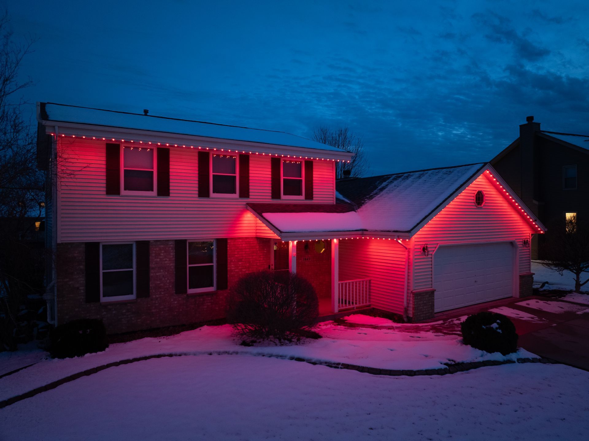 A house is lit up with red christmas lights at night.
