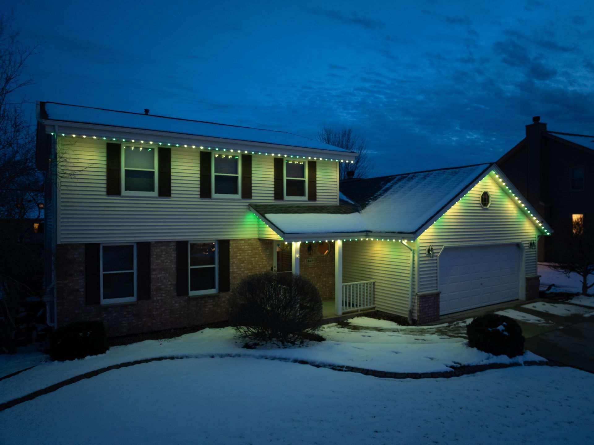 A house with yellow lights on it is covered in snow.