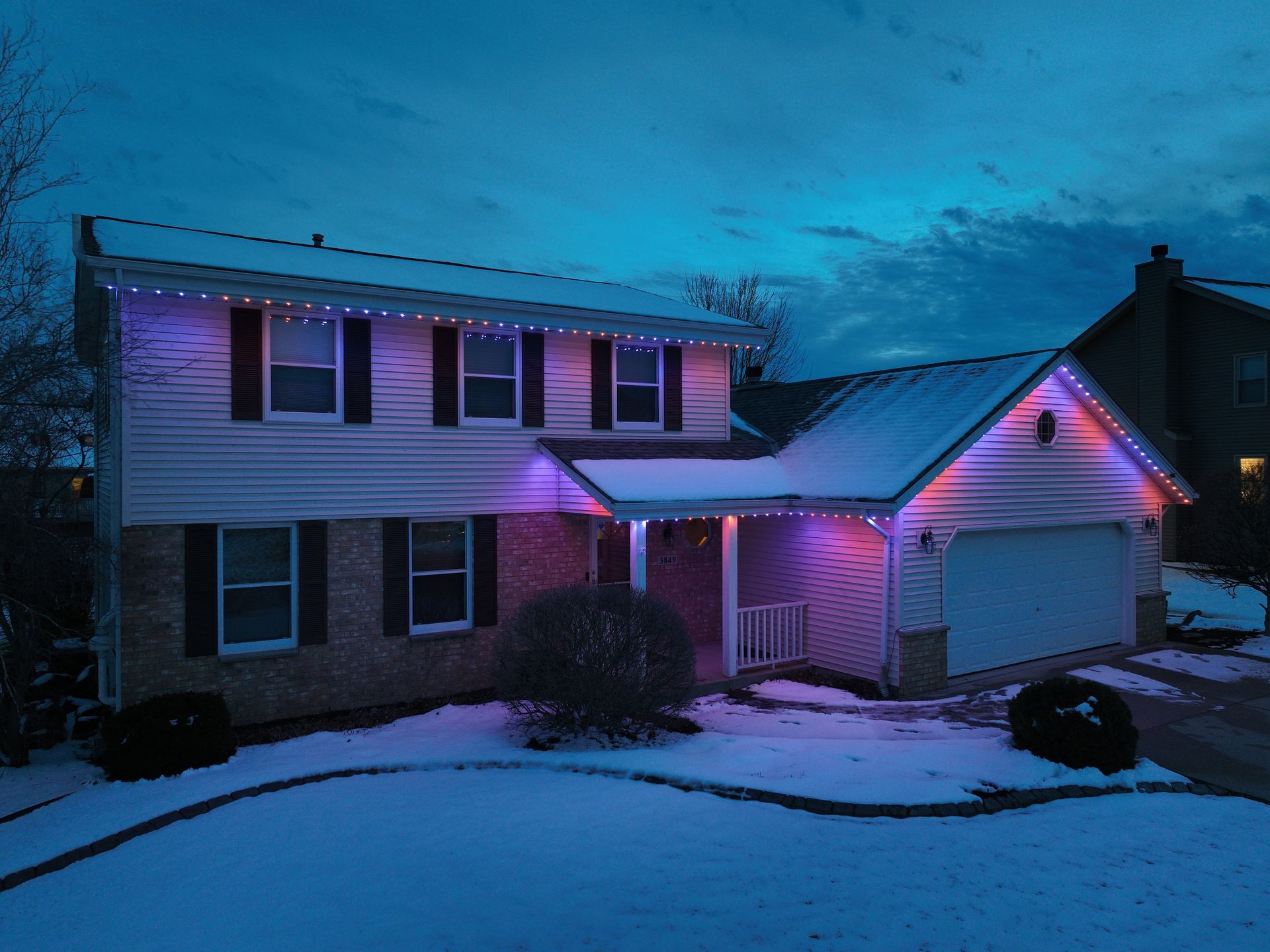 A house with Halloween thematic lights on it is covered in snow.