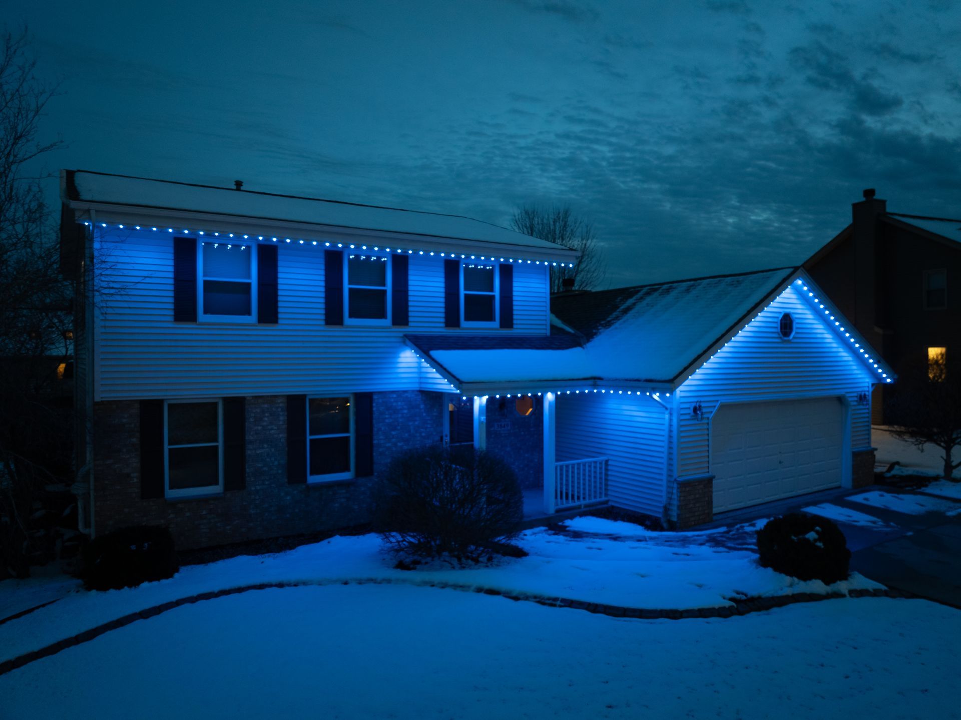 A house with blue lights on it is covered in snow.