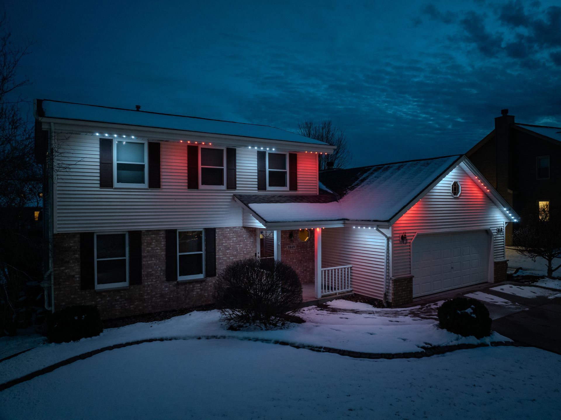A house is lit up with red and white christmas lights at night.