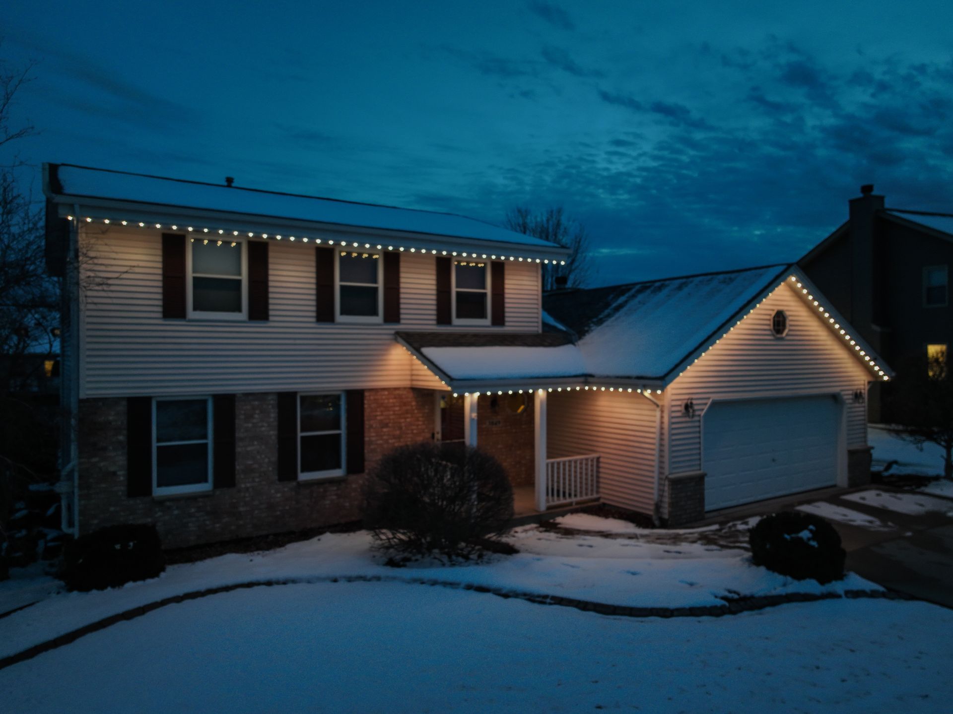 A house with orange lights on it is covered in snow.