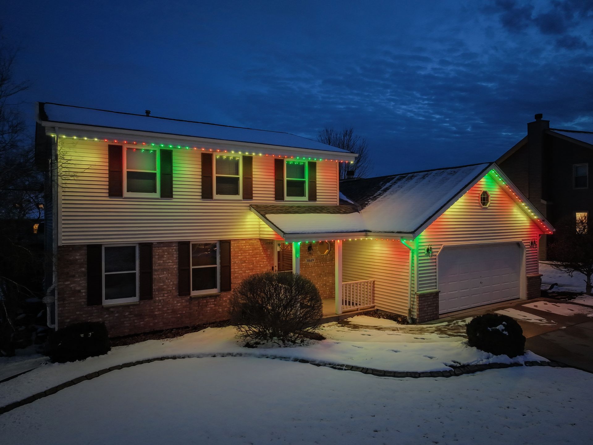 A house with very good color variety lights on it is covered in snow.