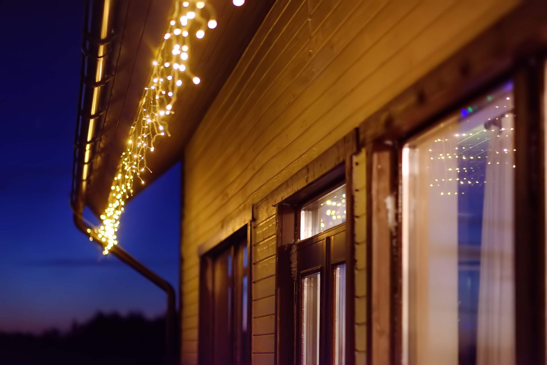 String lights hanging under a residential roof at evening time. String lights hanging under a residential roof at evening time.