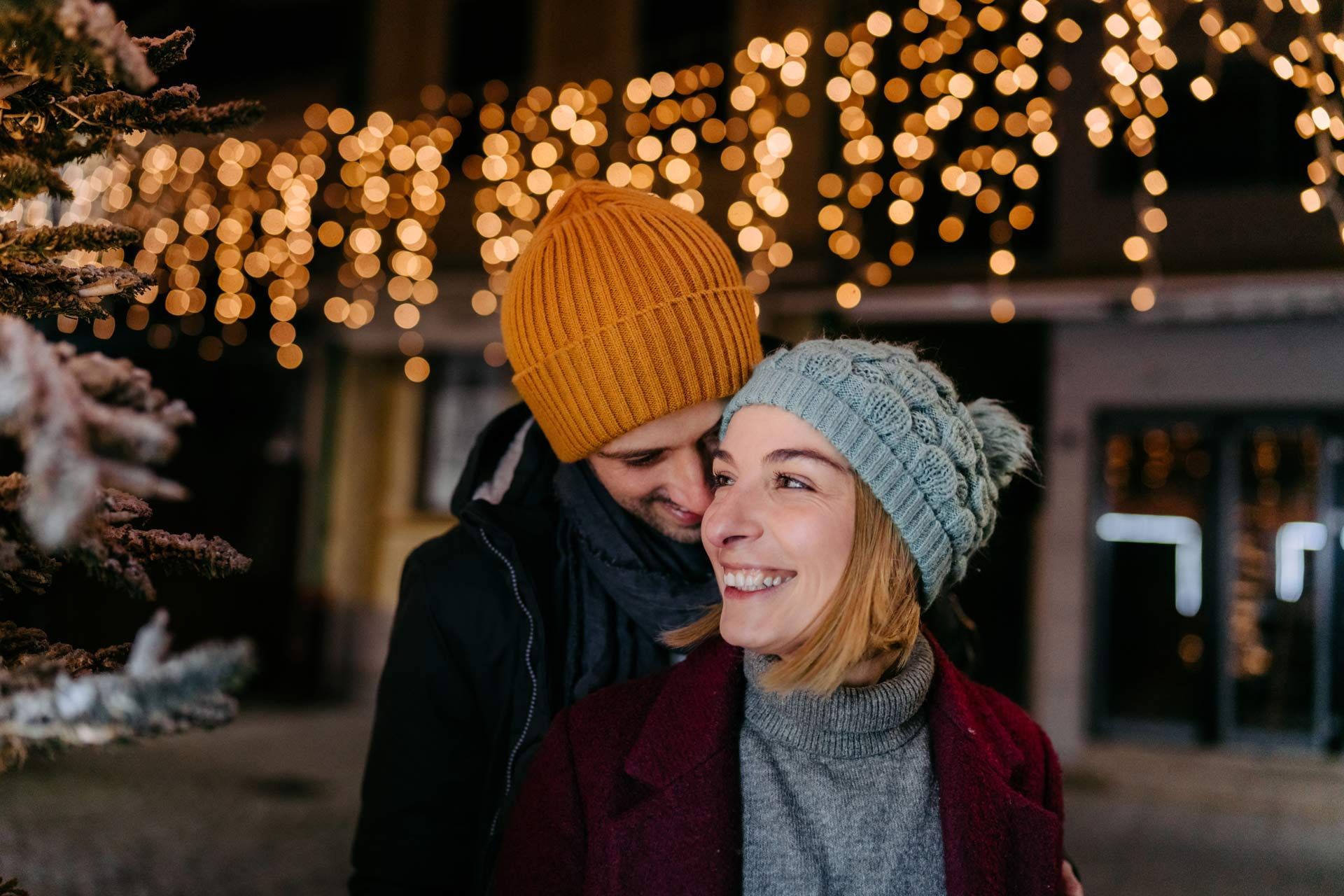 Couple in front of string lights hanging under a home at evening time. Couple in front of string lights hanging under a home at evening time.