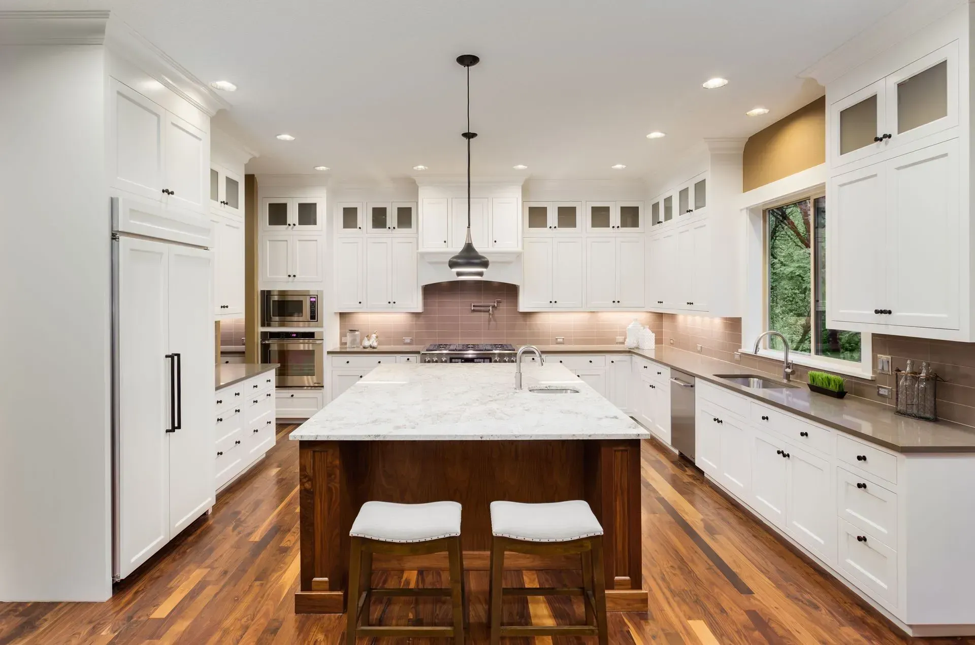 A kitchen with white cabinets and a large island in the middle.