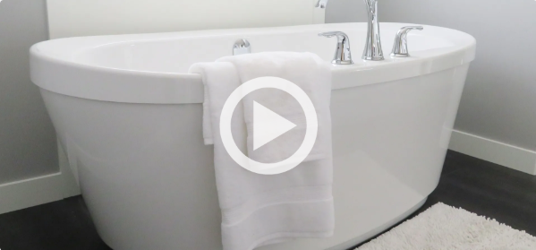 A white bathtub with a towel hanging from it in a bathroom.