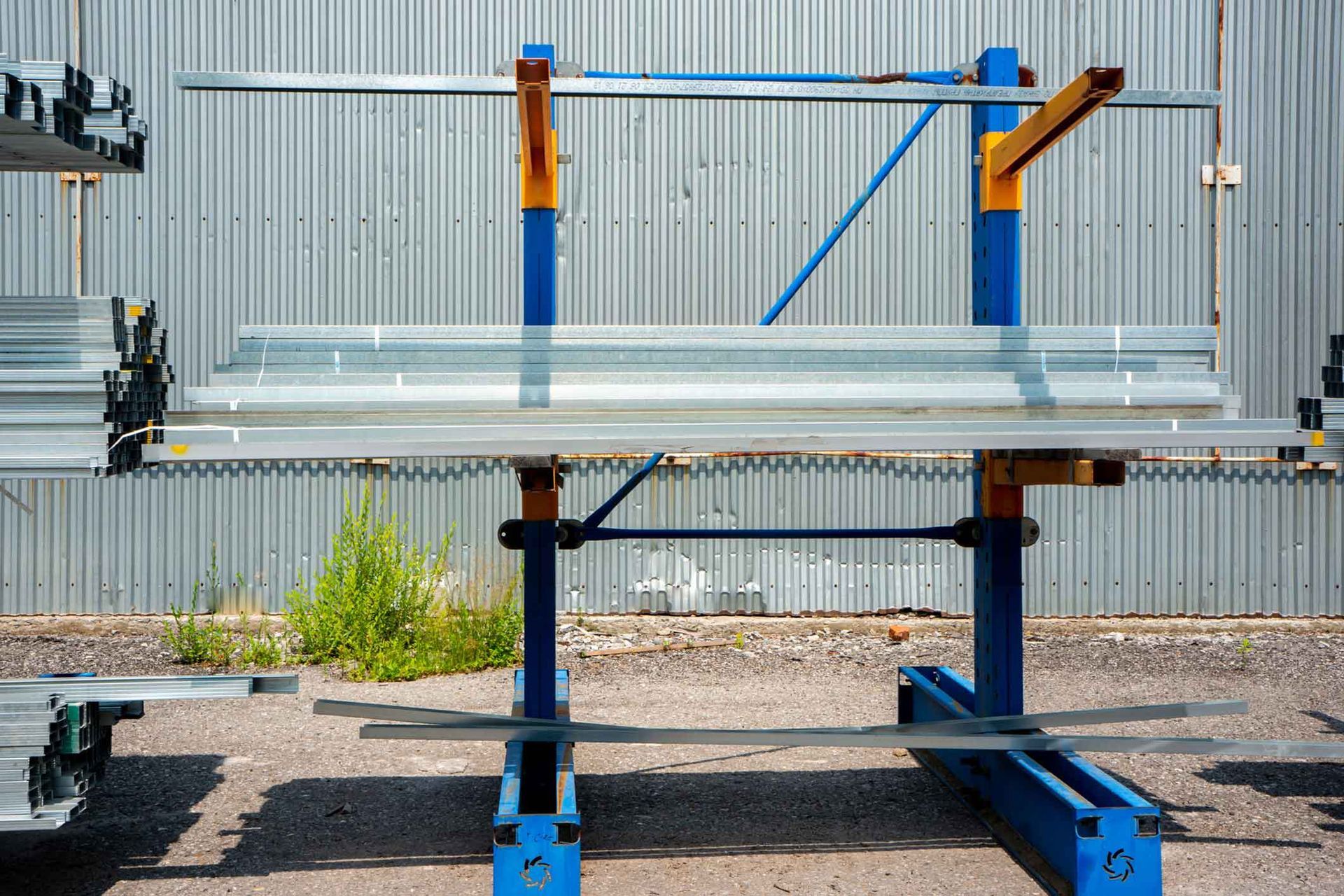 A bunch of metal pipes are sitting on a rack in front of a building.